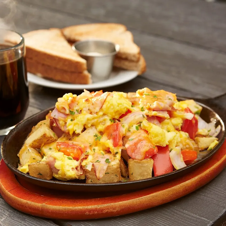 A brunch skillet of eggs, potatoes and peppers, served in a cast-iron pan