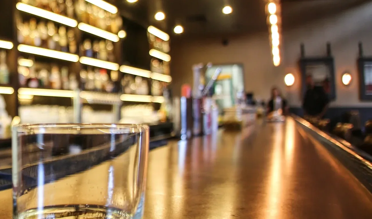 The bar at The Whisper House — a long copper-topped counter running past lit shelves of bottles