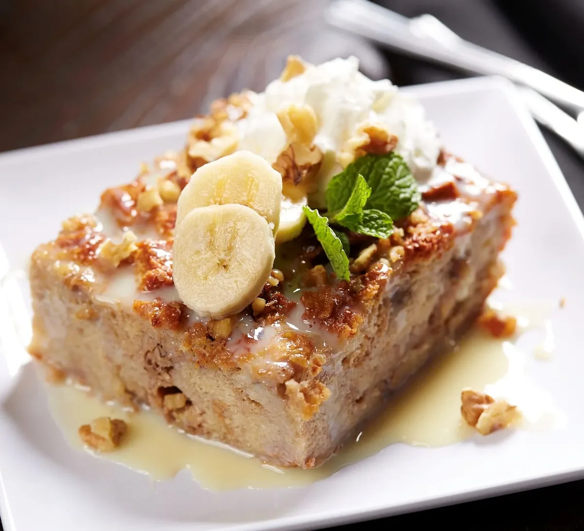 Banana bread pudding with walnuts, whipped cream and cream sauce
